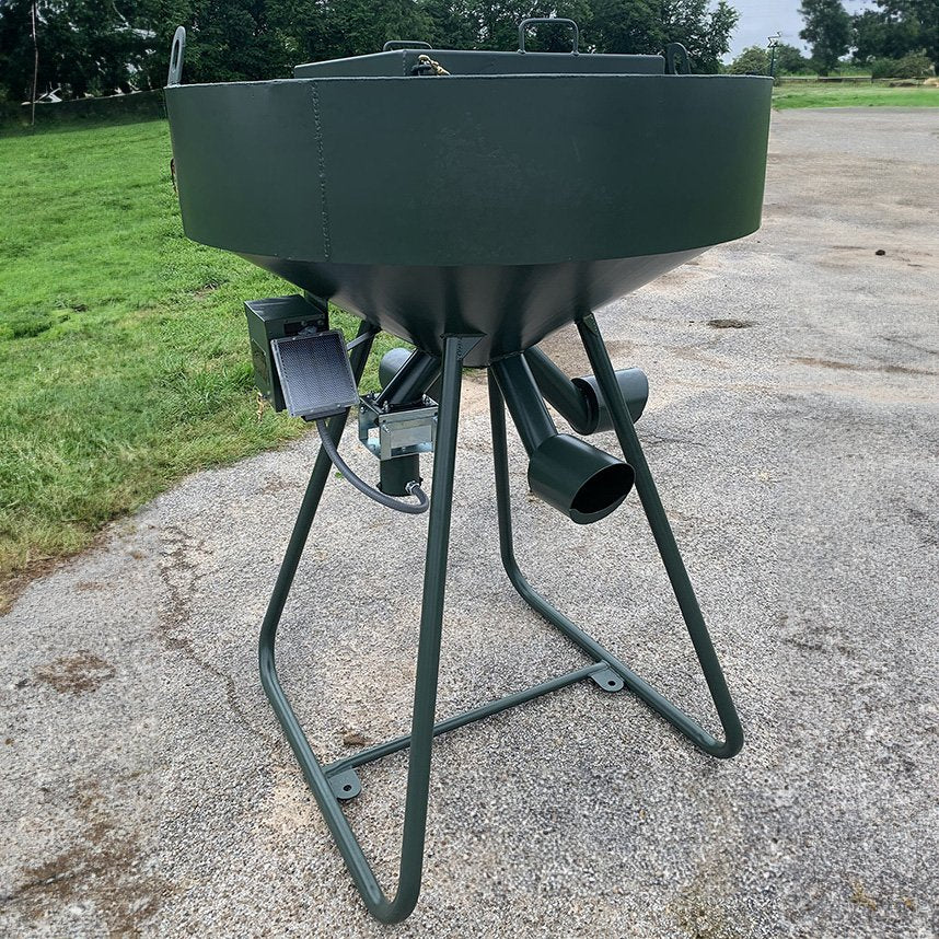 A green metal protein and corn feeder with a split capacity design, mounted on a stand, with tubes and a battery-operated mechanism.