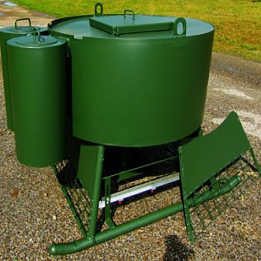 A green metal quail feeder and water station with side panels and a feed pan.