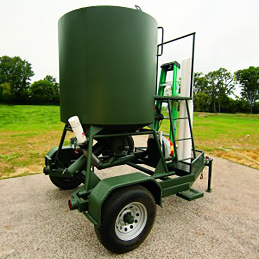 A green bulk trailer with a remote controlled 'Eliminator', tubing, fittings, ladder, and spare tire, designed for feeding.