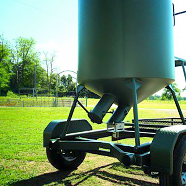 A green bulk trailer with a grain bin attached to it, parked on grass.