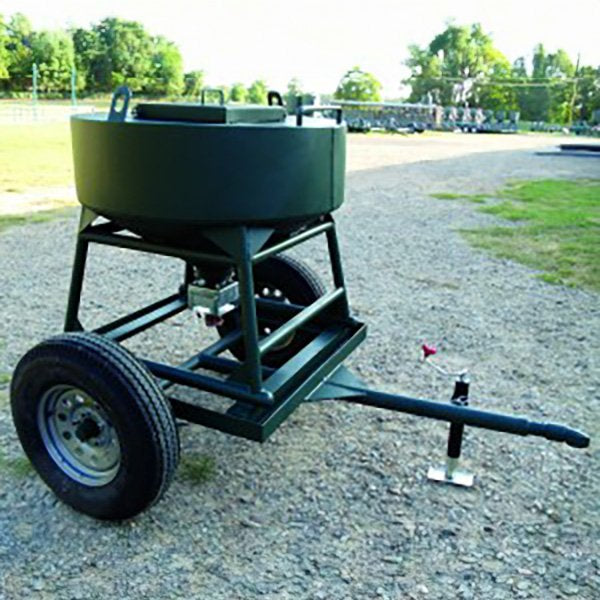 A green metal wildlife feeder with wheels and a black plastic food container, on a gravel surface.