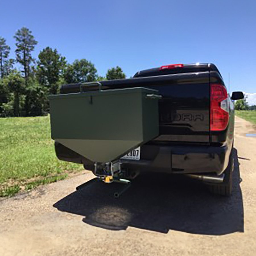 A green wildlife feeder mounted on the rear of a pickup truck.