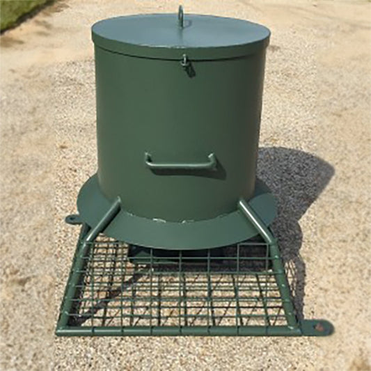 A green metal quail feeder with a hopper and a large feed tray, mounted on a metal grid base.