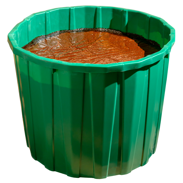 A green cylindrical lick tub filled with a brown mineral mix, designed for cattle and horses.