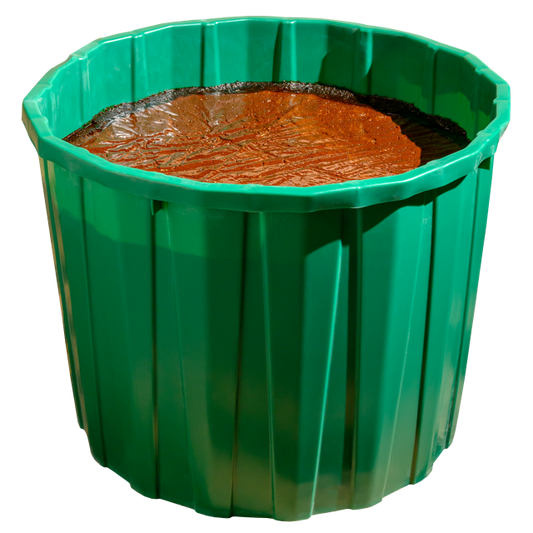 A green cylindrical lick tub filled with a brown mineral mix, designed for cattle and horses.