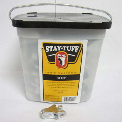 A large plastic container with a black lid labeled 'STAY-TUFF' containing silver Tee-Grips, with some Tee-Grips scattered outside the container.