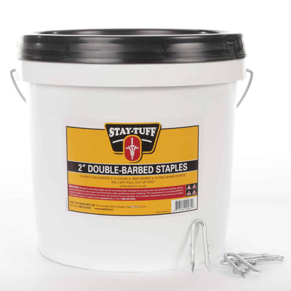 A white container with a black lid labeled 'Stay-Tuff 2" Double-Barbed Staples', containing barbed staples used for fencing.