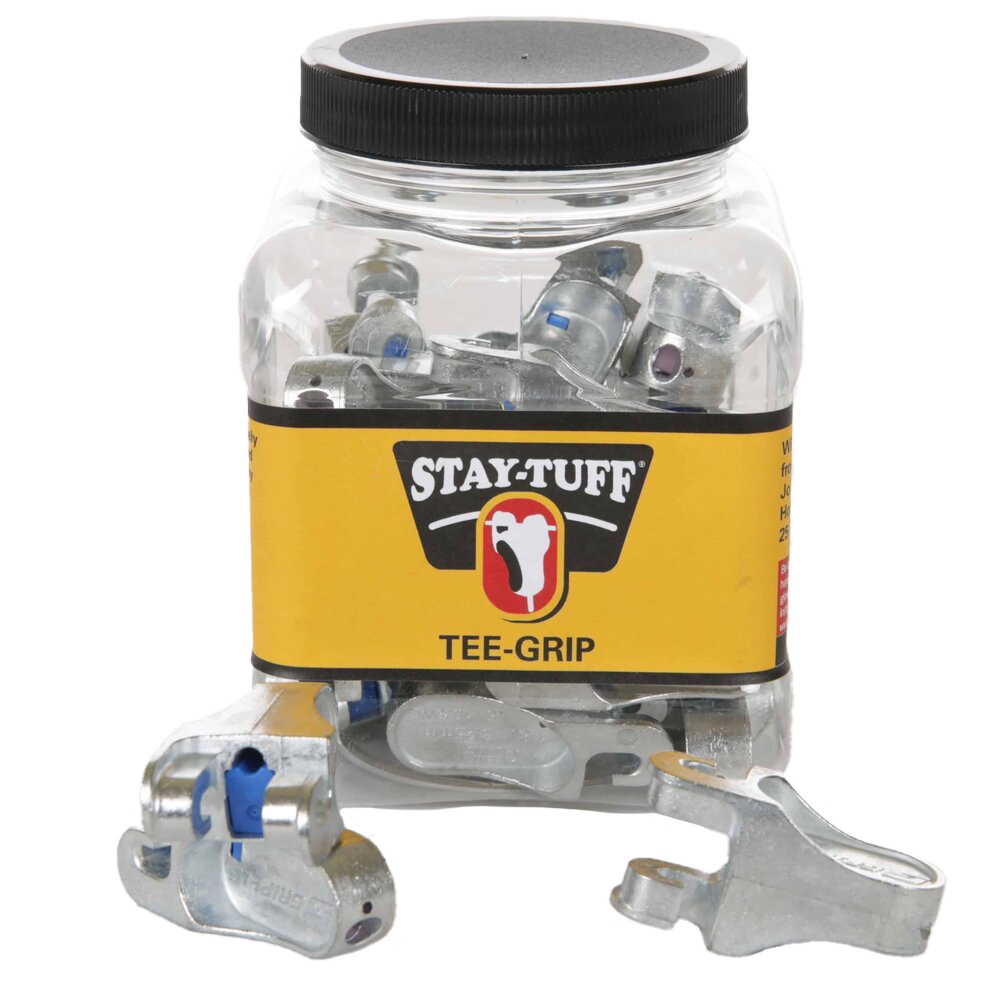 A clear plastic container with a black lid labeled 'STAY-TUFF' containing silver Tee-Grips, with some Tee-Grips scattered outside the container.