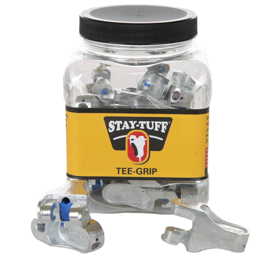 A clear plastic container with a black lid labeled 'STAY-TUFF' containing silver Tee-Grips, with some Tee-Grips scattered outside the container.