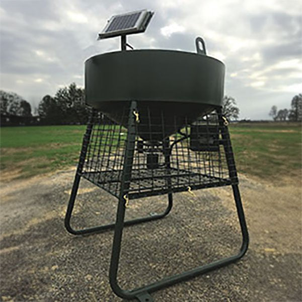 A green corn feeder with a solar panel on top, mounted on a metal frame, located outdoors.